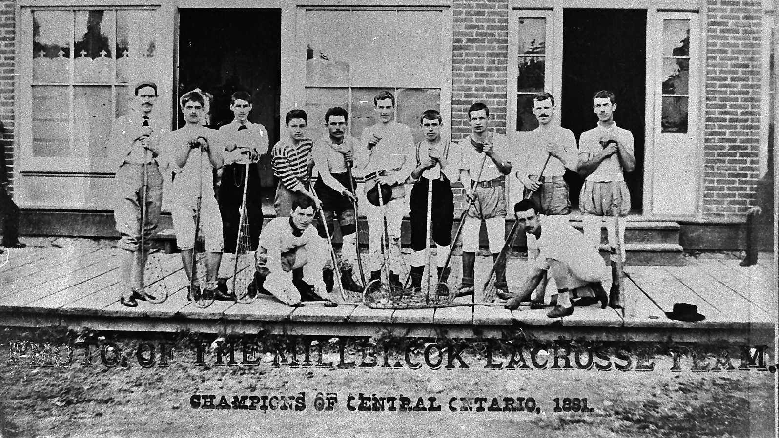 Group of lacrosse players posing on a porch, holding sticks; banner reads Champions of Central Ontario, 1891.